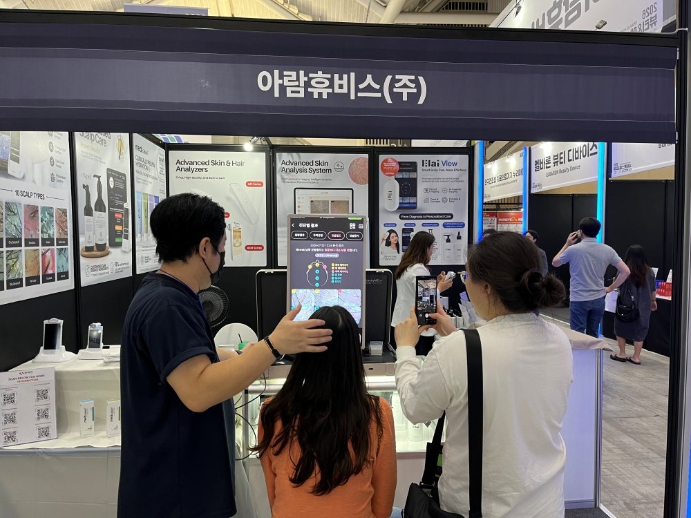 관람객이 아람휴비스 부스에서 두피 진받을 받고 있다 / 출처=IT동아